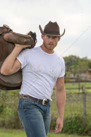muscular rugged cowboy with a saddle