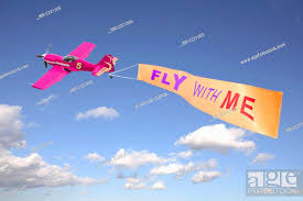 plane in the sky pulling a banner with