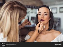 makeup artist applying model s lipstick
