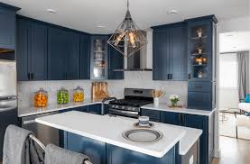 We love how this kitchen pairs the trend of dark and moody tones like deep blue and black with crisp swanbridge countertops and white cabinets for a bright and balanced space. Kitchen Trend Navy Blue Cabinets Scott Mcgillivray