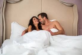 couple laughing in bed happy man and