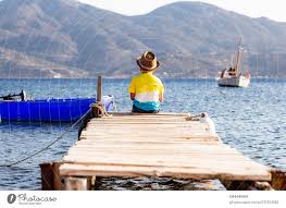 little boy on a dock sitting on his