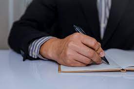 As mãos de um empresário em um terno, assinando ou escrevendo um documento  | Foto Premium