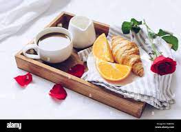Saint Valentin romantique petit-déjeuner au lit, plateau avec croissant  frais, tasse de café espresso avec du lait, des oranges et de rose rouge.  Bon matin concep Photo Stock - Alamy