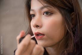 age asian applying lipstick