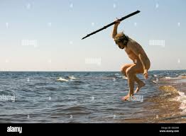 naked savage man jumping with a spear over the water Stock Photo - Alamy