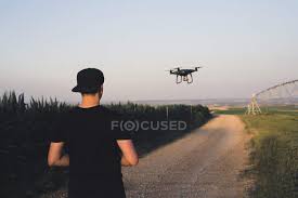 back view of man flying drone in field
