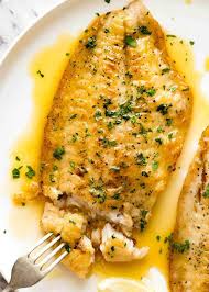 overhead photo of a crispy pan fried fish fillet drizzled with lemon er sauce and sprinkled
