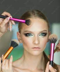 hands apply makeup on model face woman