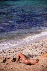 Nackte Frau beim Sonnenbaden am Strand am Meer, lizenzfreies Stockfoto