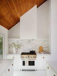 By bringing the backsplash from the countertops to the ceiling, the designer created a sizable accent wall that appears as if it was carved right out of the earth. These Backsplash Ideas Bring Out The Best Of White Kitchen Cabinets