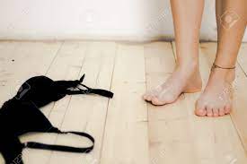 女性が服を脱ぐので、裸足と天然の堅木張りの床に横たわっている黒いブラの写真素材・画像素材 Image 93937389