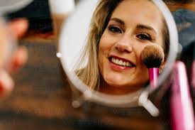 woman applying makeup in mirror stock photo