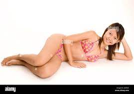 A pretty young asian model poses lying down in a bikini Stock Photo - Alamy