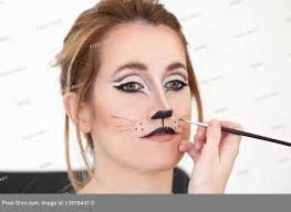 visagiste applying cat makeup onto face