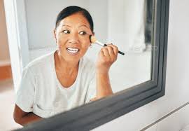 woman mirror and brush makeup in home
