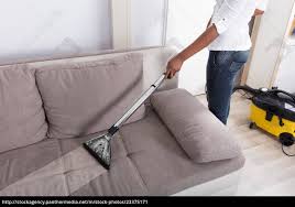 housewife cleaning sofa with vacuum