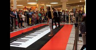 woman joins man on giant floor piano