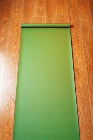 green yoga mat on wooden floor unfolded