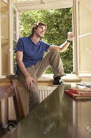 リビング ルームの窓の敷居に座る若い男の写真素材・画像素材 Image 19076805