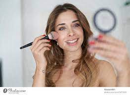 smiling young woman applying make up