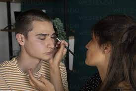 young woman applying makeup on man