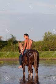Junge cowboys mit nacktem oberkörper neben pferd stehend