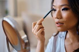 young asian woman applying eyeshadow