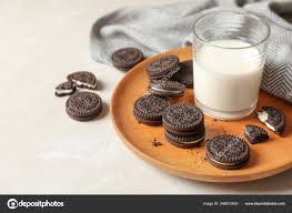 Plate With Chocolate Sandwich Cookies And Milk On Table