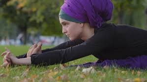 Muslim Woman in Hijab Sits on Green Grass Lawn in Park Bends in Body Doing  Fold Female Stretching by jm_video