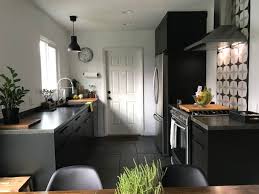 Fantastic kitchen features white upper cabinets and navy blue lower cabinets paired with white quartz countertops and a white glass tiled backsplash. Black Kitchen Cabinets Apartment Therapy