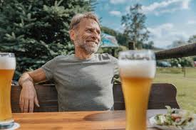 Smiling mature man looking away while sitting in beer garden stock photo