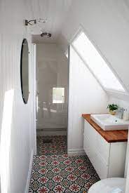 A spacious attic bathroom in gray and white with a large swath of glass mosaic tile beneath the slanted roof. 15 Attics Turned Into Breathtaking Bathrooms