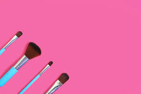 a set of four makeup brushes on a pink
