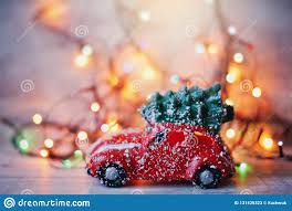 Little Red Car Toy Carrying Christmas Tree In Snow And Bokeh