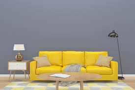 Are you the type of person who always sticks to neutrals—who can't seem to escape the best white paint colors, best brown paint colors, and best greige paint colors when it comes to decorating your home? Gray Wall With Yellow Sofa On Wood Floor Stock Photo