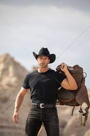 hot rugged cowboy with a saddle on a