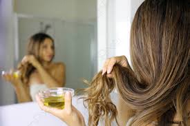 young woman applying olive oil mask to