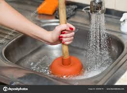 woman cleans plunger with clogged sink