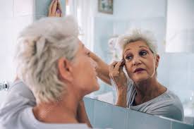 senior woman applying makeup stock