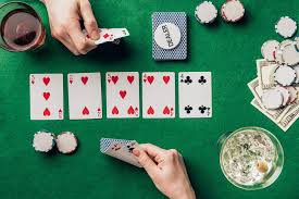 Man and woman with cards playing poker by table with drinks and chips  Royalty-free Photo and Stock Image