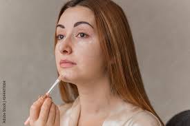 woman applying foundation and concealer