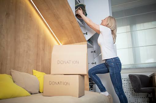 A woman preparing a Donation box while decluttering.