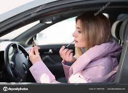 young woman applying makeup car traffic