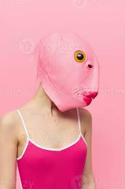 a woman in a pink fish head mask stands