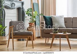 Maybe you would like to learn more about one of these? Real Photo Of An Armchair With A Book Standing Next To A Small Table With Pot And Sofa With Cushions In Cozy Living Room Canstock