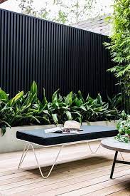 It will not rot like a wood barrier does, nor will it receive insect damage that could require a premature replacement. Black Corrugated Metal Fencing In A Contemporary Garden Setting With Lush Architectural Fo Courtyard Gardens Design Contemporary Garden Small Courtyard Gardens