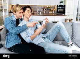 Happy gay couple in love spend time together at home. Two homosexual guys  lying down on