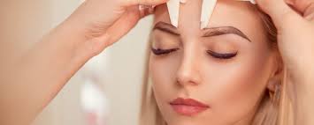 stylist mering the eyebrows with the ruler micropigmentation work flow in a beauty salon woman having her eye brows tinted with semi permanent makeup