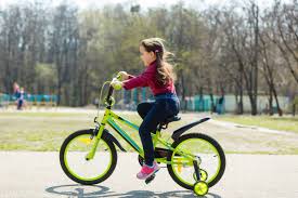 Adorable little girl riding a bike in a city — daytime, looking - Stock  Photo | #440840152